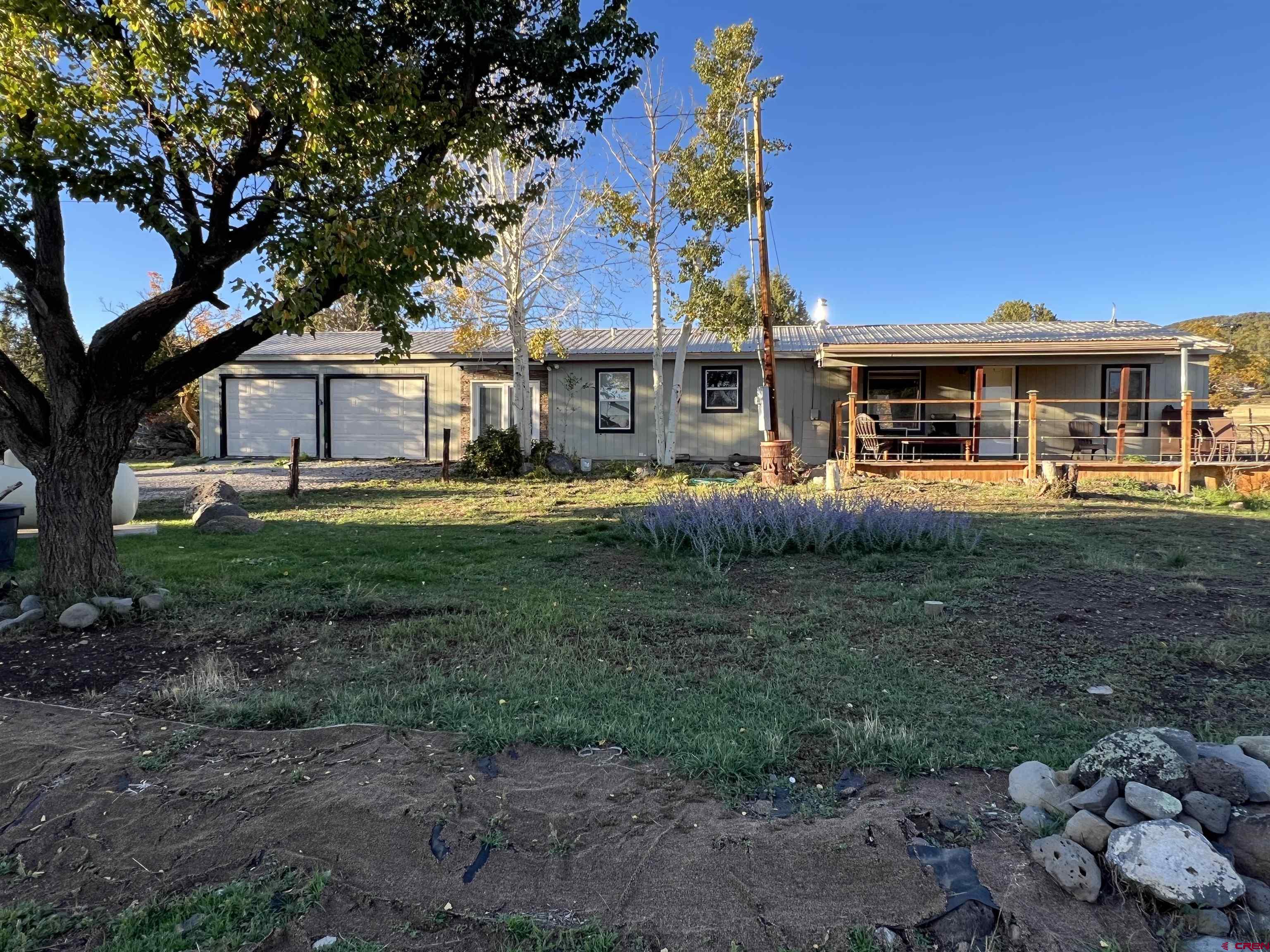 20246 2375th Road Cedaredge, CO 81413 - Photo 1 of 18 a front view of a house with a garden and trees