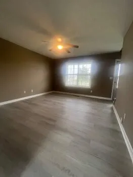 an empty room with wooden floor and windows