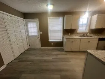 a kitchen with granite countertop a sink a stove top oven and wooden floor