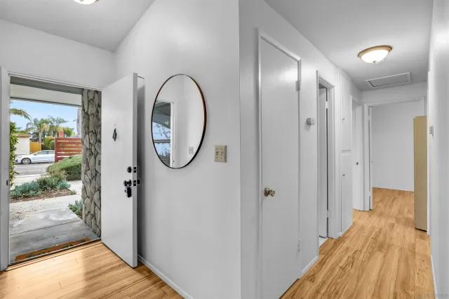 a view of a hallway with wooden floor and a bathroom