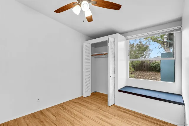 an empty room with wooden floor fan and windows