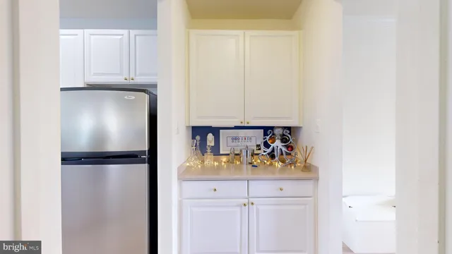 a view of a refrigerator in kitchen with white cabinets
