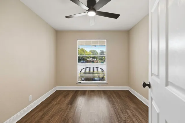 a view of an empty room with wooden floor and a window