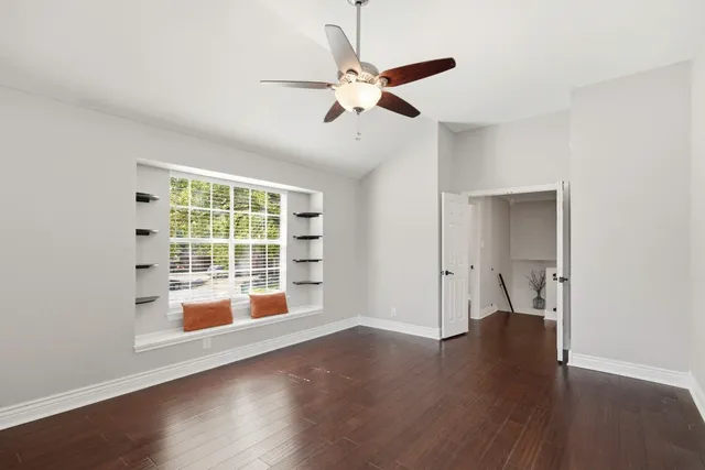 a view of empty room with wooden floor and fan