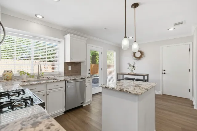 a kitchen with a stove a sink a kitchen island with wooden floor and cabinets