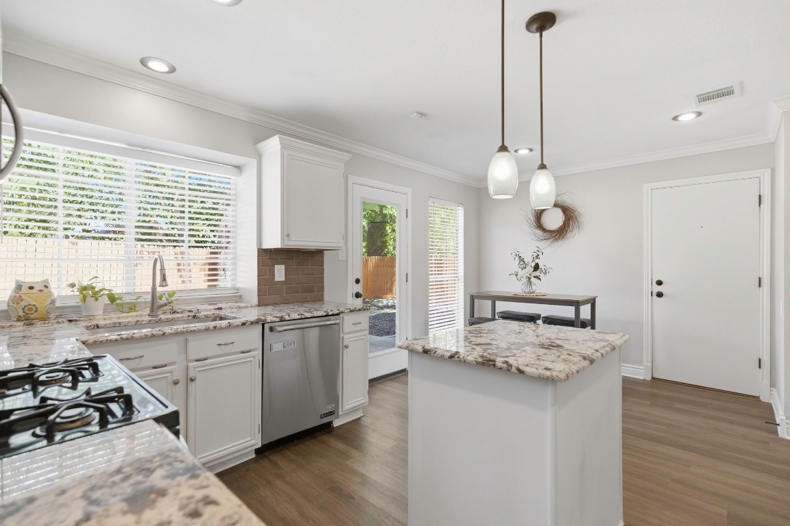 1108 Red Bird Drive Cedar Park, TX 78613 - Photo 7 of 30 a kitchen with a stove a sink a kitchen island with wooden floor and cabinets