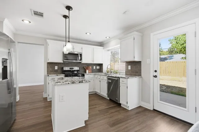 a kitchen with stainless steel appliances granite countertop a refrigerator a stove top oven a sink and dishwasher with wooden floor