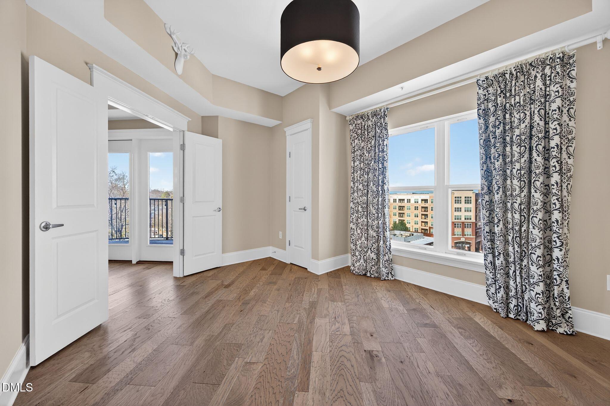 222 Glenwood Avenue, Unit 605 Raleigh, NC 27603 - Photo 19 of 60 an empty room with wooden floor and windows