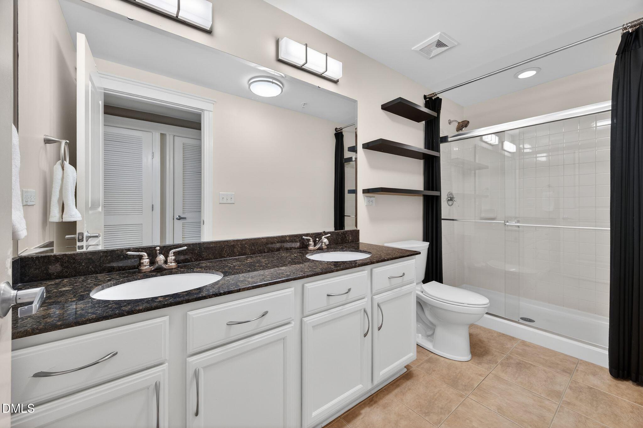 222 Glenwood Avenue, Unit 605 Raleigh, NC 27603 - Photo 30 of 60 a bathroom with a granite countertop sink a toilet and a mirror