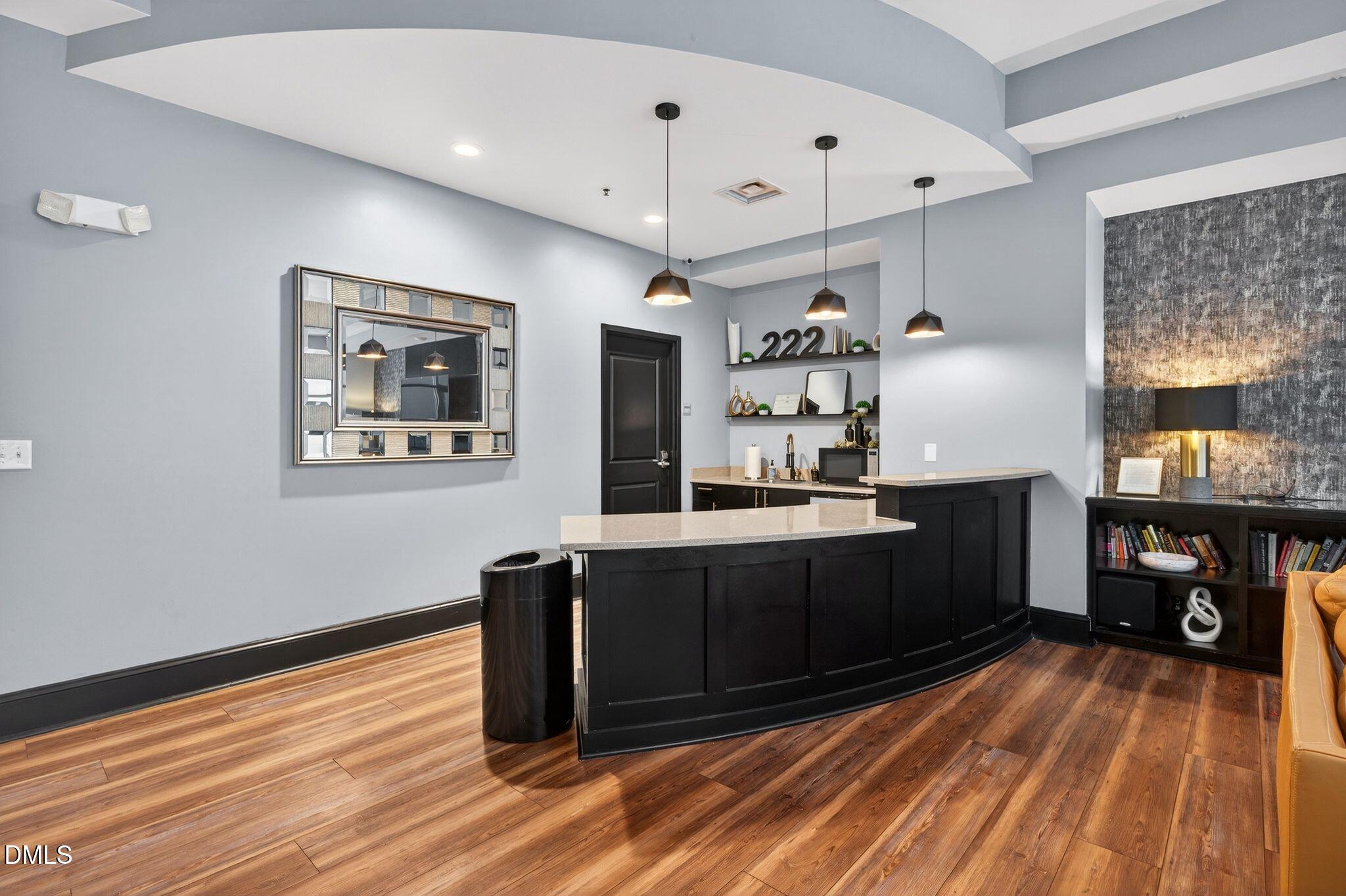 222 Glenwood Avenue, Unit 605 Raleigh, NC 27603 - Photo 56 of 60 a kitchen with stainless steel appliances wooden floor and chandelier