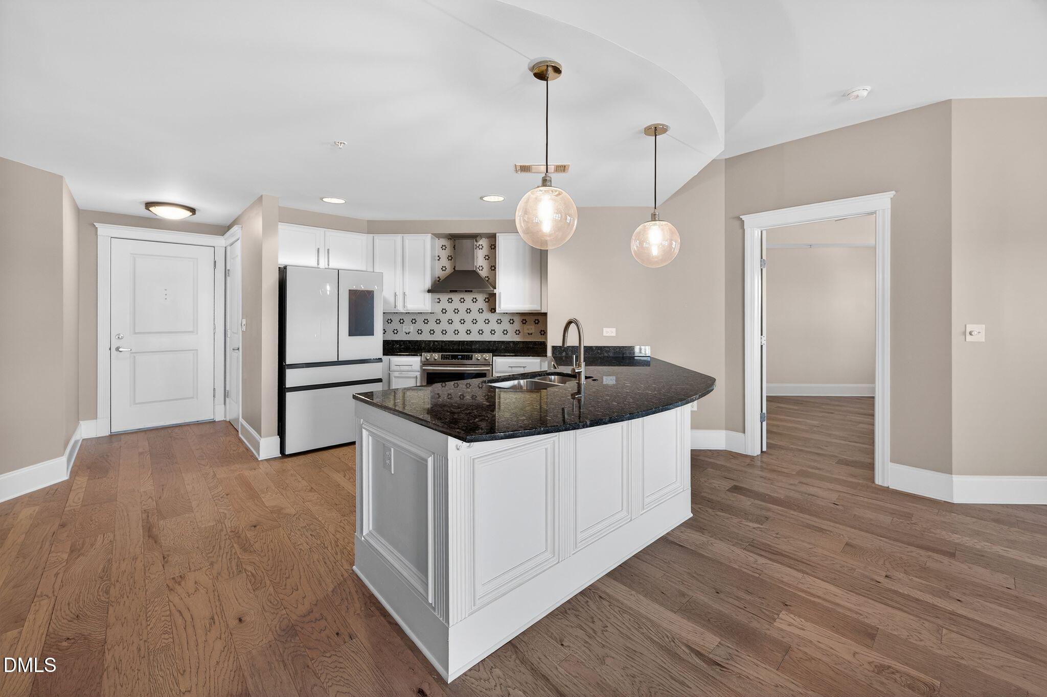 222 Glenwood Avenue, Unit 605 Raleigh, NC 27603 - Photo 9 of 60 a kitchen with stainless steel appliances a sink a refrigerator a center island a stove and wooden floor