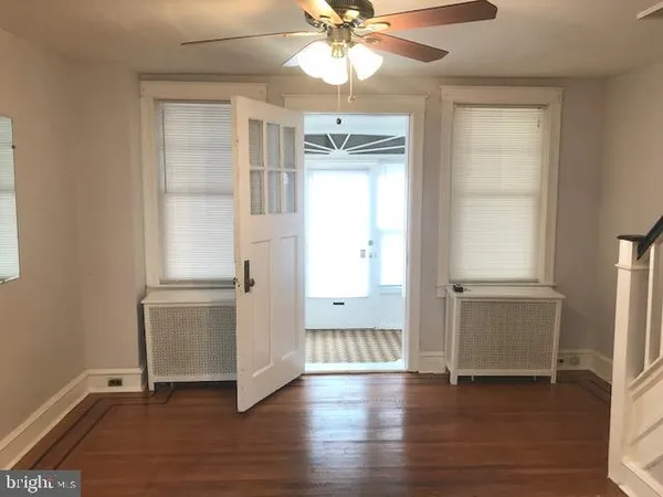 an empty room with wooden floor closet and windows