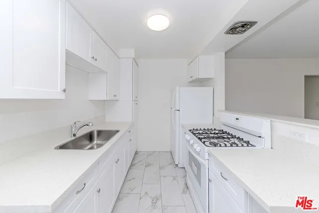 a kitchen with granite countertop a sink stove and cabinets