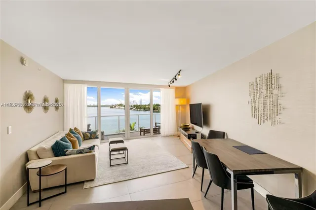 a living room with furniture a flat screen tv and a floor to ceiling window
