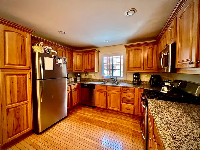 a kitchen with granite countertop stainless steel appliances a refrigerator a stove top oven and cabinets