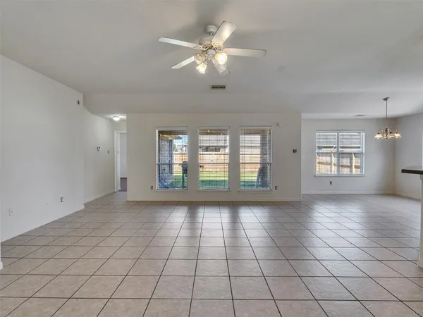 a view of an empty room with a window and a kitchen