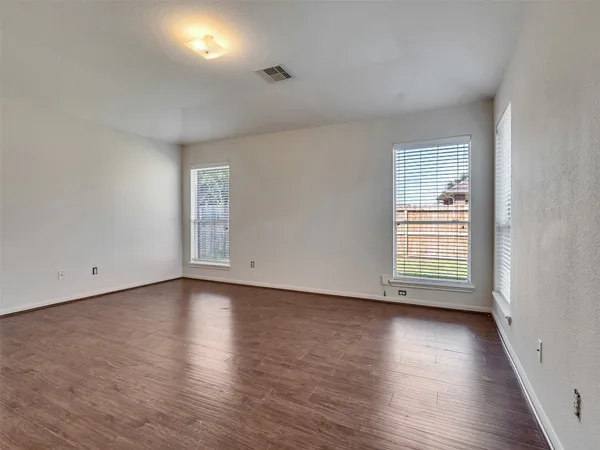an empty room with wooden floor and windows
