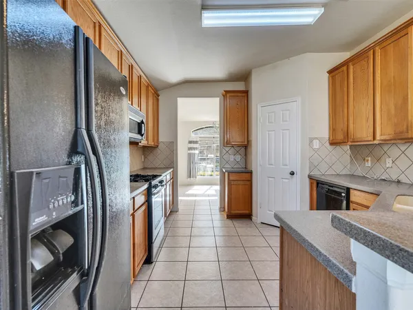 a kitchen with stainless steel appliances granite countertop a refrigerator a stove and a sink with cabinets
