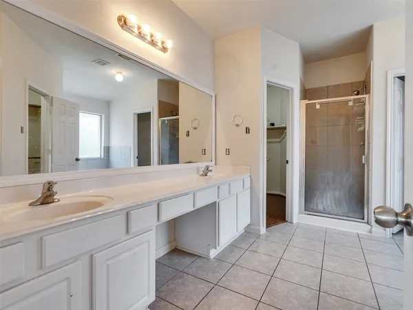 a spacious bathroom with a shower a sink and a mirror