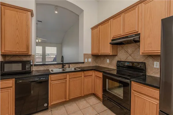 a kitchen with granite countertop a stove sink and cabinets