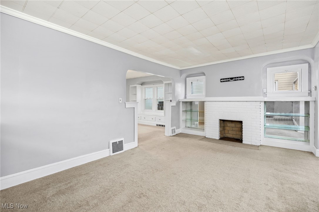 3368 Berea Road Cleveland, OH 44111 - Photo 2 of 26 Unfurnished living room featuring crown molding, carpet flooring, and a fireplace