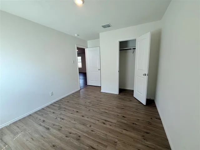 a view of an empty room with wooden floor and closet