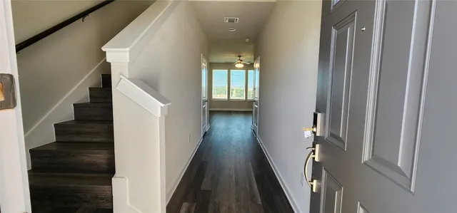 a view of a hallway with wooden floor and staircase