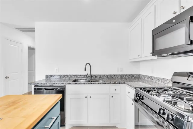 a kitchen with stainless steel appliances granite countertop a stove a sink and a microwave