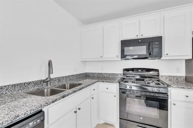 a kitchen with granite countertop a sink stove and microwave