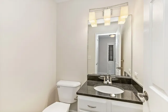 a bathroom with a granite countertop sink toilet and mirror