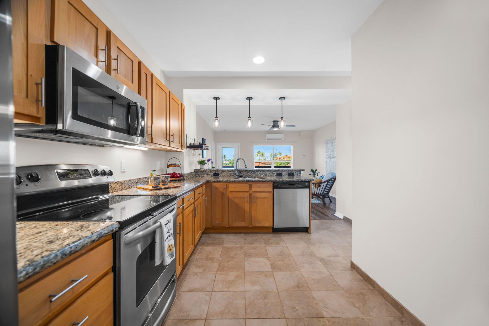 3708 Lower Honoapiilani Road, Unit E33 Lahaina, HI 96761 - Photo 6 of 36 a large kitchen with stainless steel appliances granite countertop a stove a sink and a microwave
