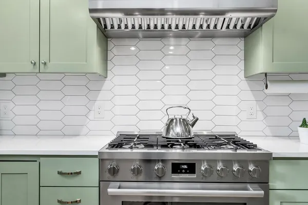 a stove sitting inside of a kitchen with white cabinets