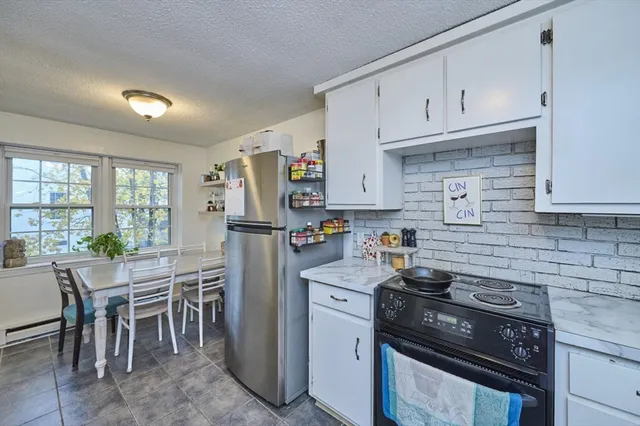 a kitchen with granite countertop a stove chairs and refrigerator