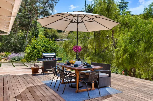 a patio with wooden floor a yard a table and chairs