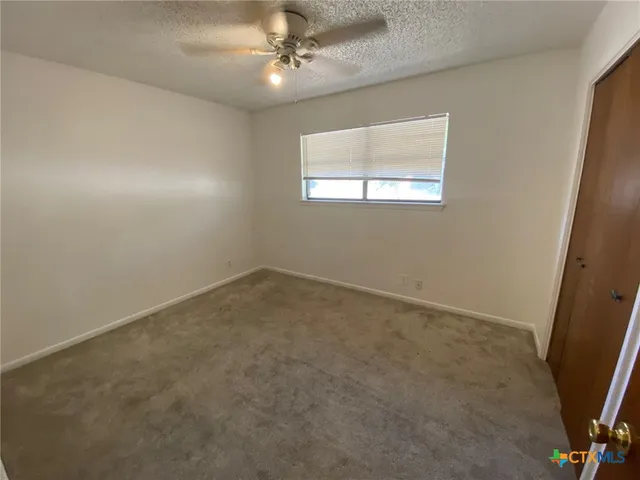 an empty room with a ceiling fan and a window