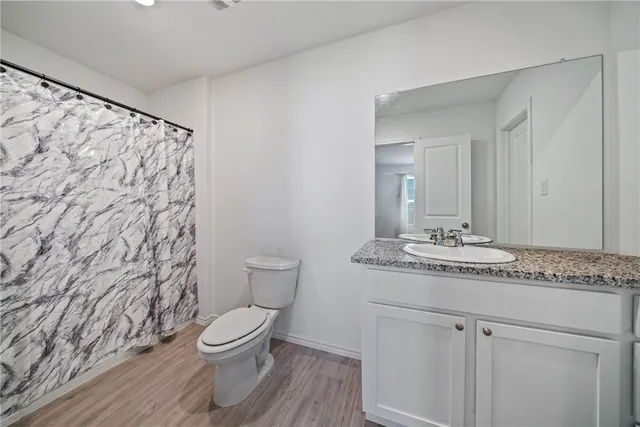 a bathroom with a granite countertop sink toilet and mirror