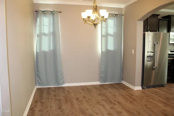 a view of a hallway with wooden floor and chandelier