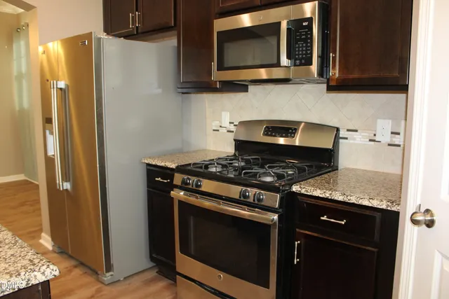 a kitchen with stainless steel appliances granite countertop a stove microwave and refrigerator