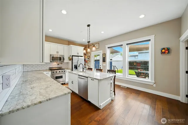 a large kitchen with kitchen island a large counter space a sink appliances and cabinets