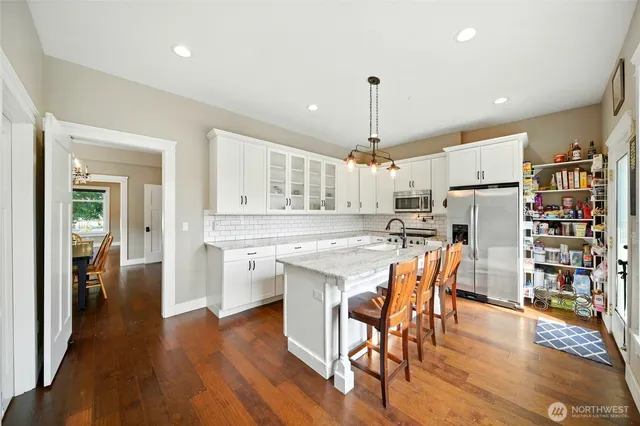 a kitchen with stainless steel appliances a dining table chairs and wooden floor