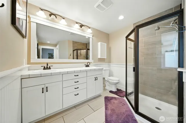 a spacious bathroom with a double vanity sink toilet mirror and shower