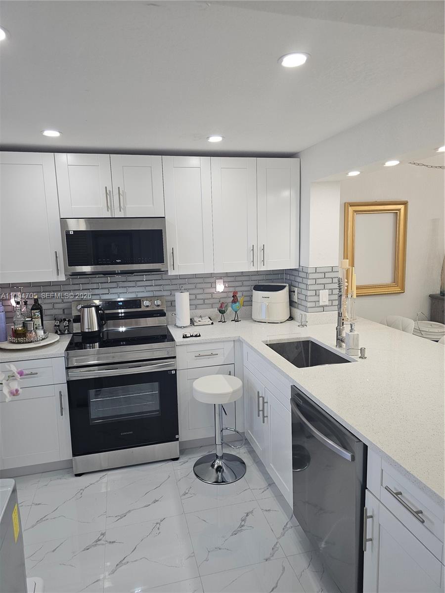 3910 Inverrary Boulevard, Unit 703B Lauderhill, FL 33319 - Photo 25 of 30 a kitchen with a sink a stove and cabinets