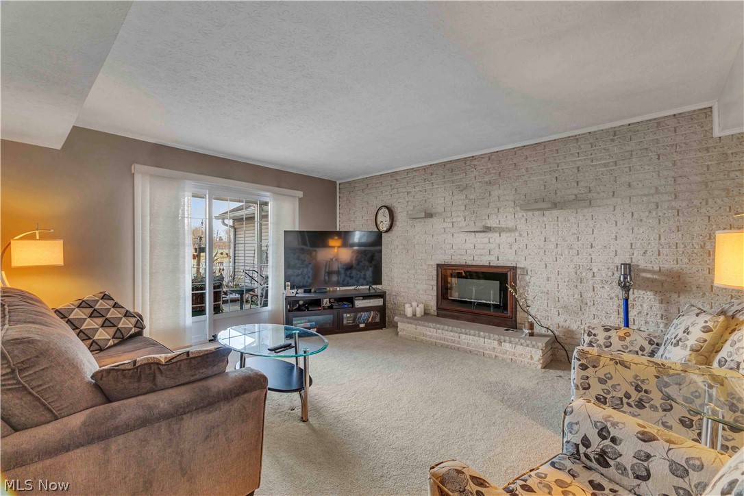 563 North Carpenter Road Brunswick, OH 44212 - Photo 3 of 45 Carpeted living area with a textured ceiling, a fireplace, and brick wall