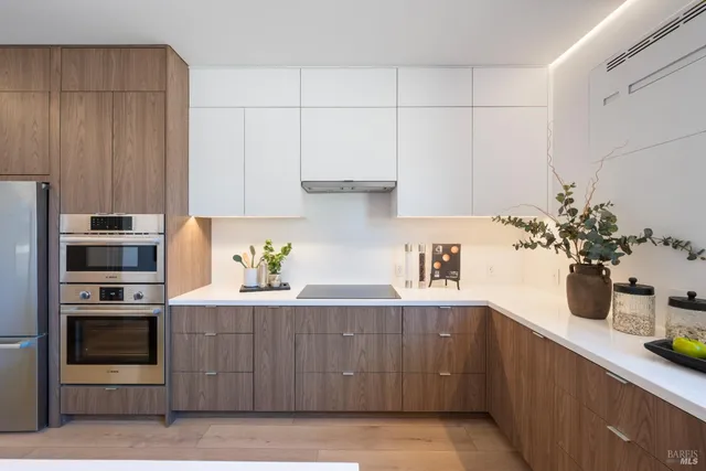 a kitchen with stainless steel appliances granite countertop a coffee maker a sink and white cabinets
