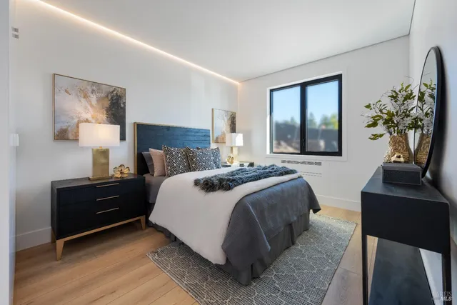 a bedroom with a bed lamp and a potted plant on a dresser