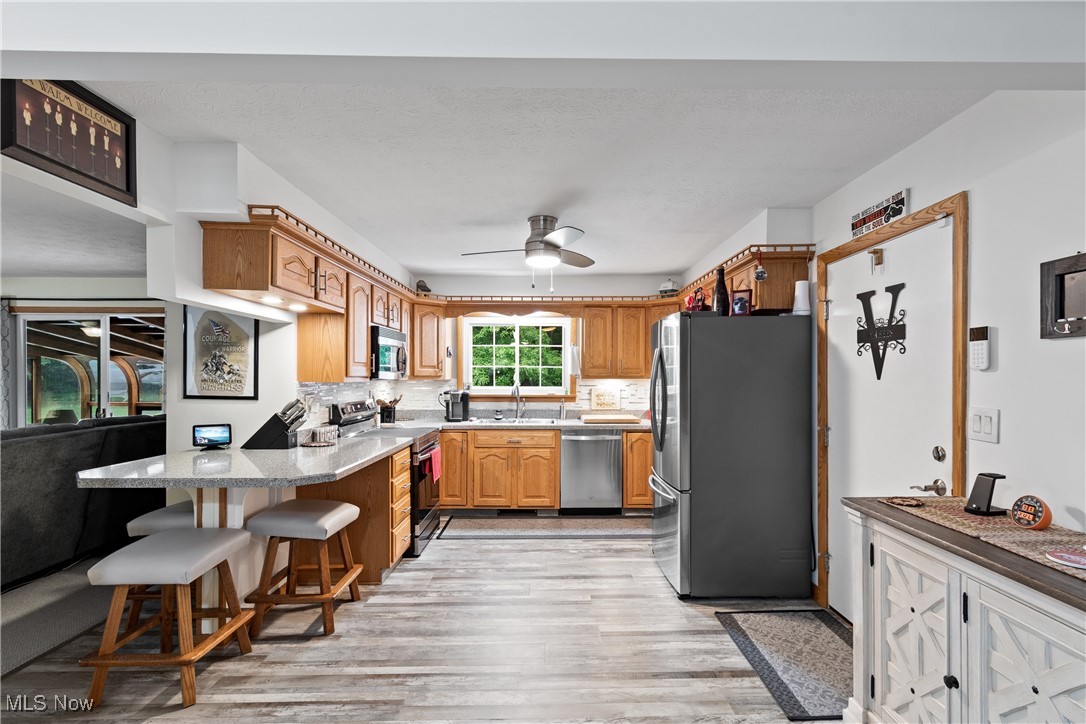 4640 Sherman Road Kent, OH 44240 - Photo 13 of 37 Kitchen with stainless steel appliances, a peninsula, light wood-style floors, tasteful backsplash, and light countertops