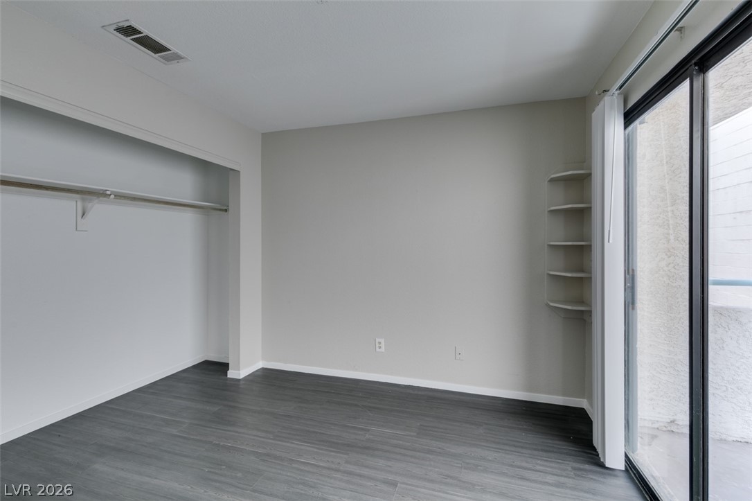 810 North Sloan Lane, Unit 103 Las Vegas, NV 89110 - Photo 6 of 16 Unfurnished bedroom with dark wood finished floors, baseboards, and a closet