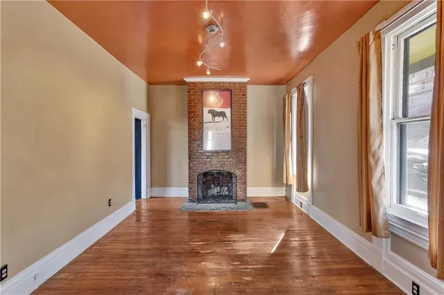 a view of an empty room with fireplace and windows