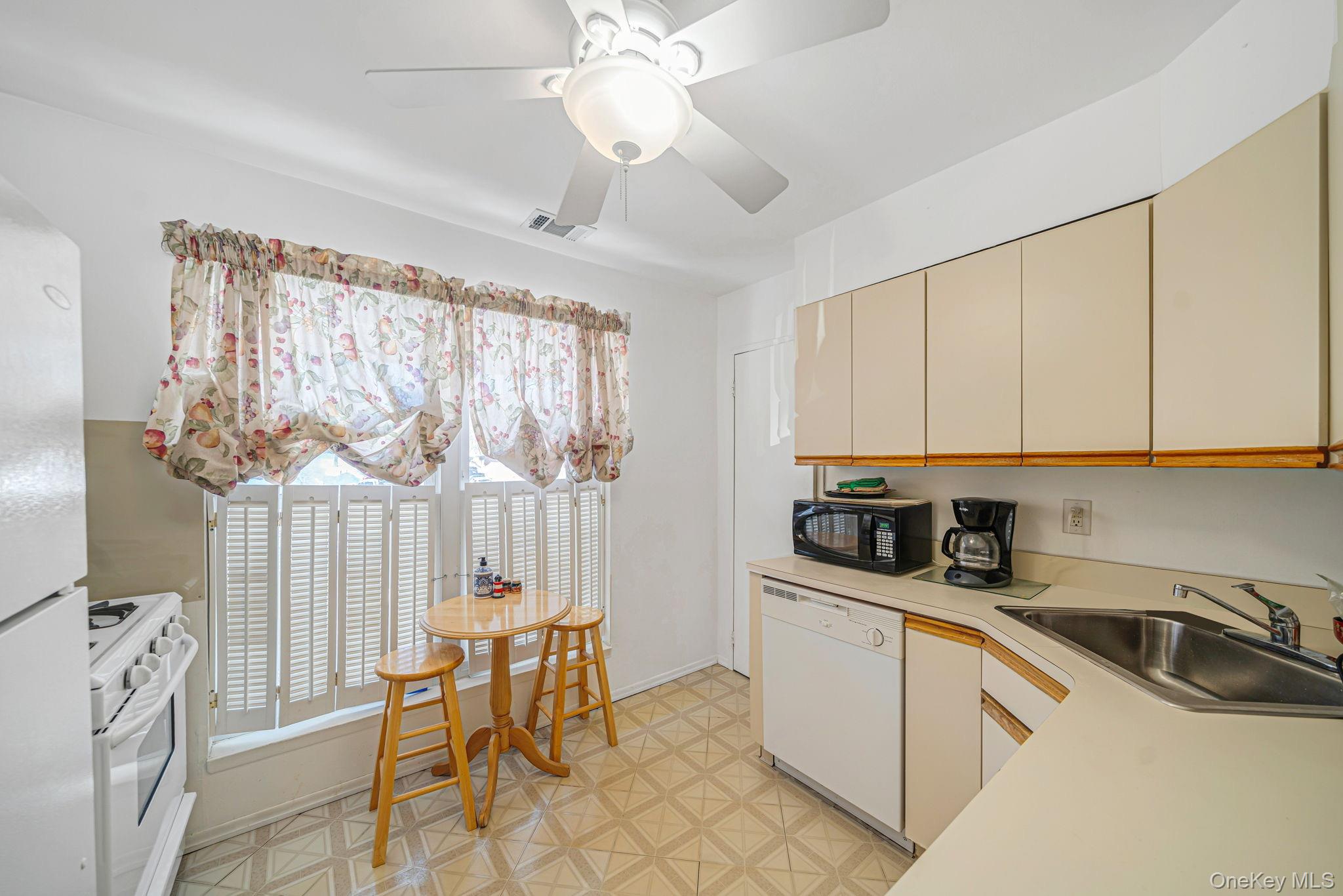 8 Juniper Court, Unit 8 Selden, NY 11784 - Photo 4 of 14 Kitchen featuring light floors, light countertops, white appliances, cream cabinetry, and ceiling fan