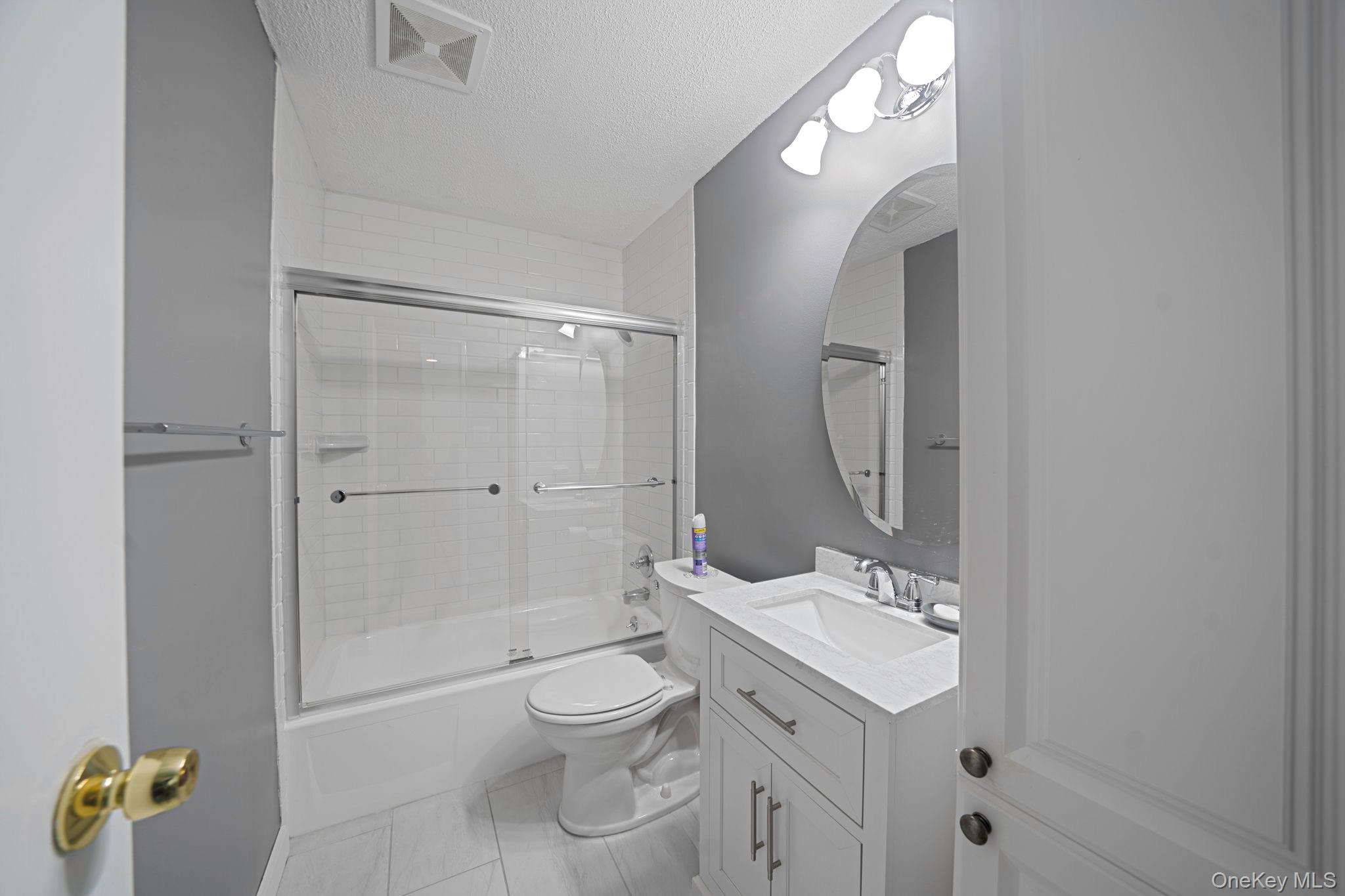 8 Juniper Court, Unit 8 Selden, NY 11784 - Photo 8 of 14 Newly renovated bathroom featuring vanity, a textured ceiling, and enclosed tub / shower combo